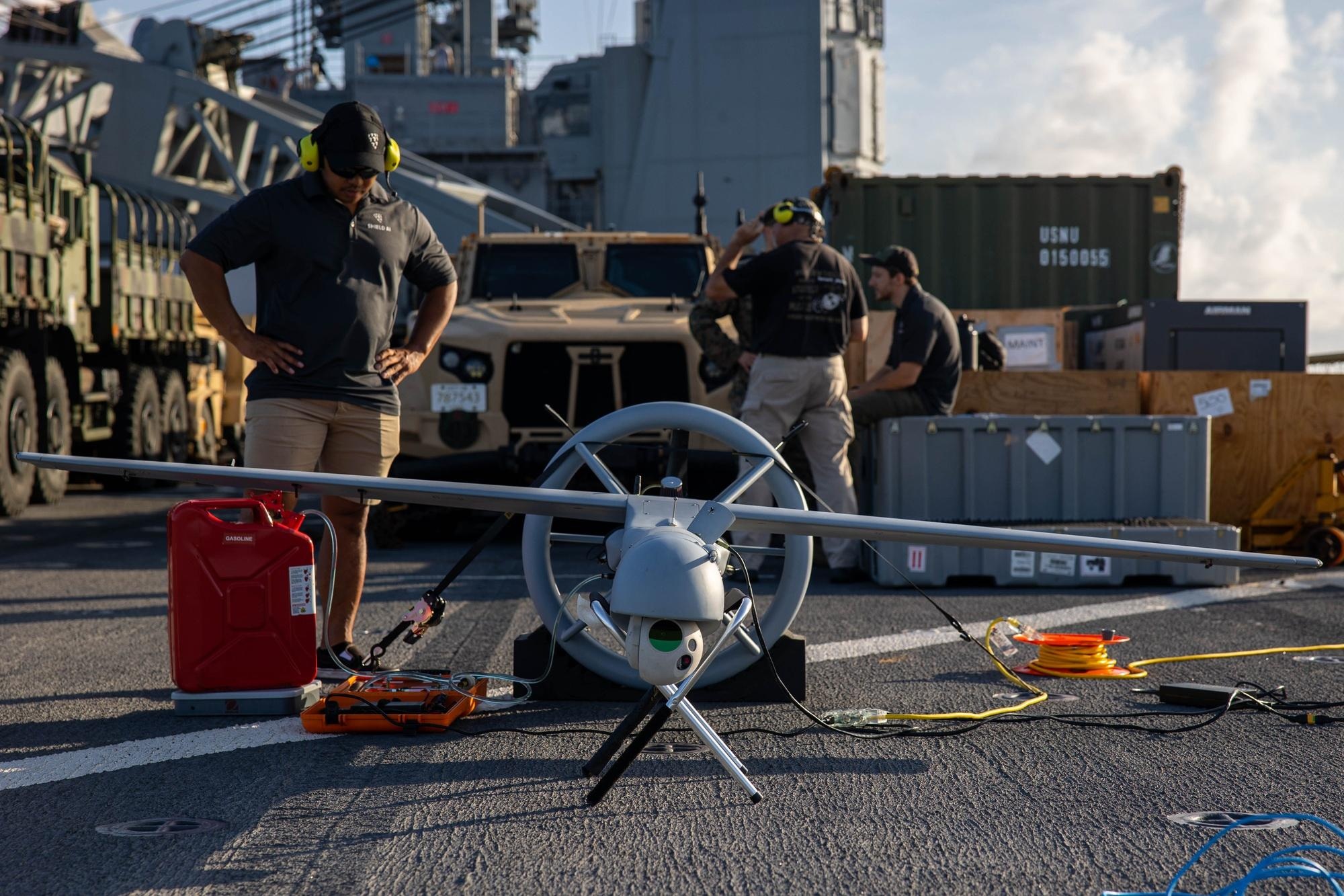 Contractors preparing a V-BAT drone on a warship deck